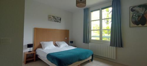a bedroom with a bed with a blue blanket and a window at Appartement Duplex Rez Jardin in Montbrun-les-Bains