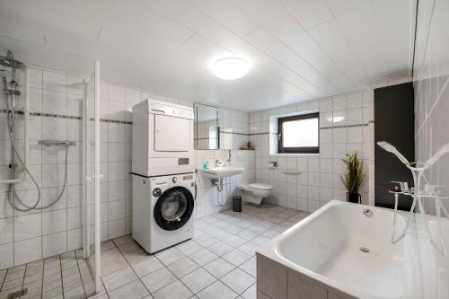 a white bathroom with a washing machine in a tub at Haus Seezeit in Freilingen
