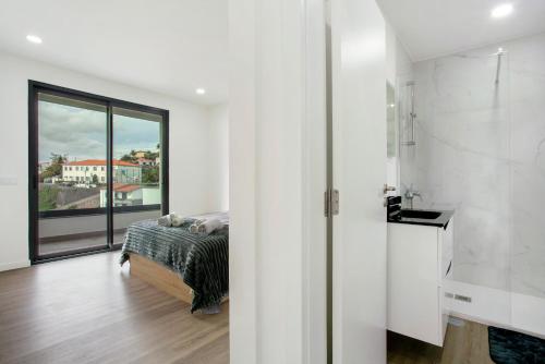 a white bedroom with a bed and a large window at Villa Angela in Funchal