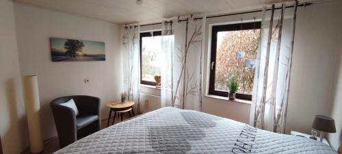 a bedroom with a bed and a chair and two windows at Sauerland Alm Winterberg 5 mit Pool in Hallenberg