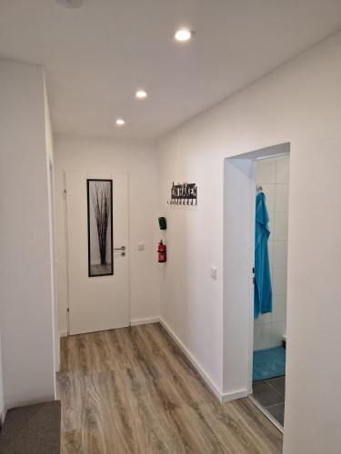 a hallway with white walls and a bathroom with a shower at Wohnung Barbarossa in Rommelhausen