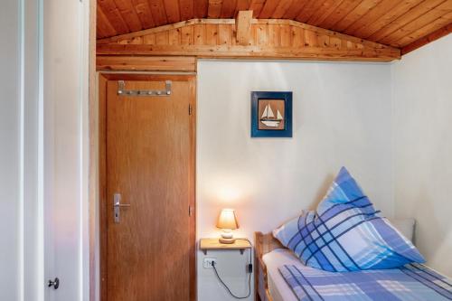 a small bedroom with a bed and a wooden door at Ferienwohnung Kleiner Strandfloh in Wangerooge