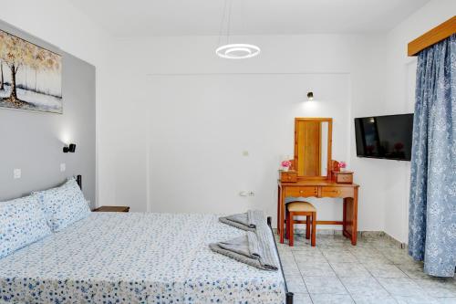 a bedroom with a bed and a desk and a television at Athina seaside in Kardamaina