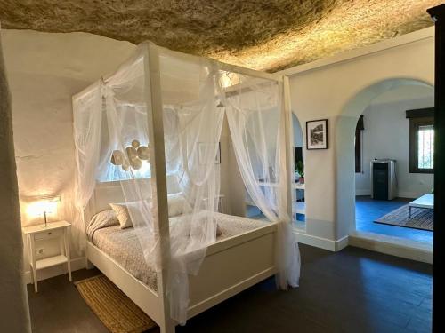 a bedroom with a canopy bed with white curtains at Avalon in Setenil in Setenil