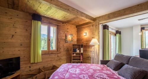 a room with wooden walls and a bed and a couch at Ferme Le Coup d'Oeil in Taninges