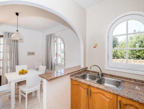 an arched kitchen with a sink and a table at Girasol Garden Superior 2-d in Menorca