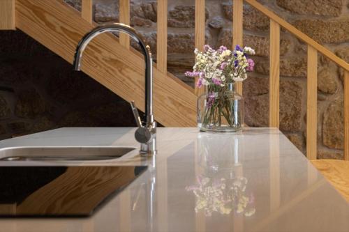a vase of flowers sitting on a counter next to a sink at Casa Da Eira in Vila Real