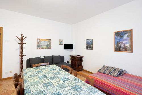a room with two beds and a table and a couch at Residence Malibu Appartamento 4 in Falcade