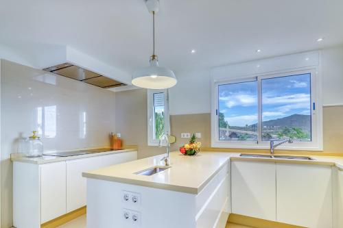 a kitchen with white cabinets and a sink and a window at Villa Ginevra in Arona