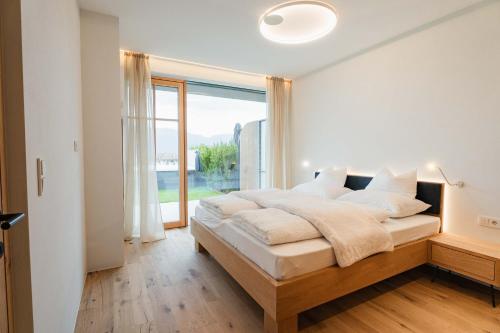 a bedroom with a large bed and a large window at Valentinerhof Apt Aqua in San Michele