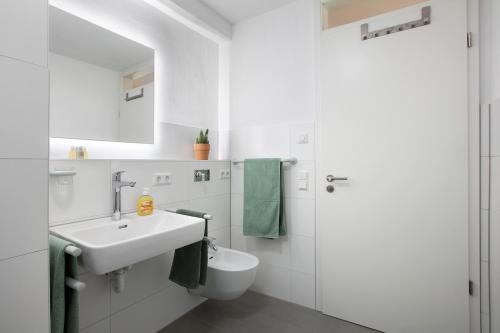 a white bathroom with a sink and a toilet at Ferienwohnung am Klemmbach in Müllheim