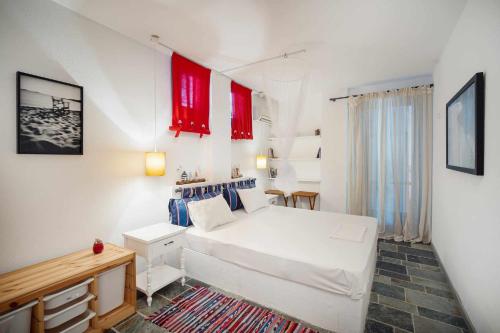 a bedroom with a white bed and red windows at Almira in Livadi