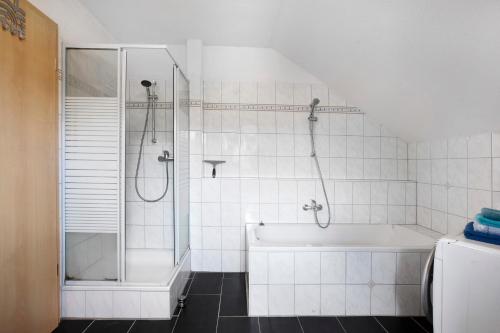 a white bathroom with a shower and a tub at Haus Castellbergblick Dachgeschoss in Ballrechten