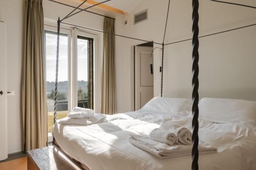 a bedroom with a bed with white sheets and towels at Borgo Syrah in Cortona
