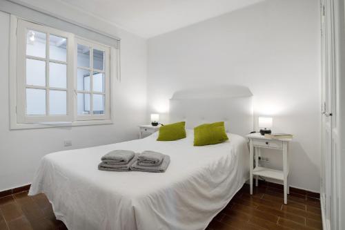 a white bedroom with a white bed with green pillows at Apartamento White Sun in Playa Honda