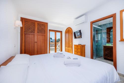 a bedroom with a large white bed and a bathroom at Sa Torre I in Canyamel
