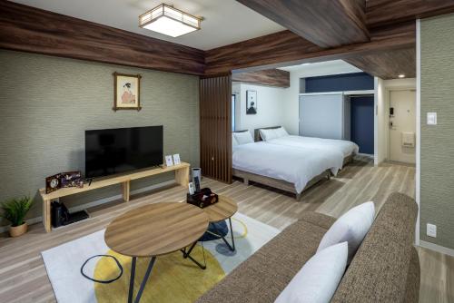 a hotel room with a bed and a tv at エクセレンス大阪城公園 Osaka Castle Suite - Best for Cherry Blossoms & Park Views - Central Stay in Osaka
