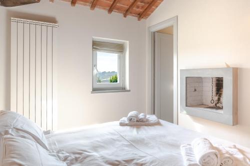 a white bedroom with a bed and a fireplace at Borgo Syrah in Cortona