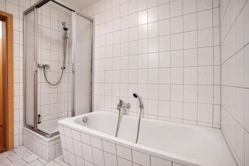 a white tiled bathroom with a tub and a shower at Haus Seeadler Wohnung 10 in Koserow