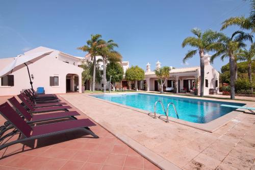 a swimming pool with lounge chairs and a house at Quinta dos Fontanais in Tavira
