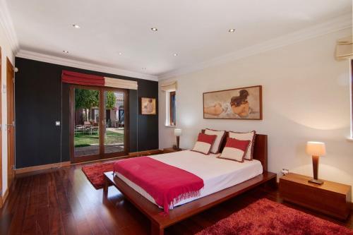 a bedroom with a large bed with a red blanket at Quinta dos Fontanais in Tavira