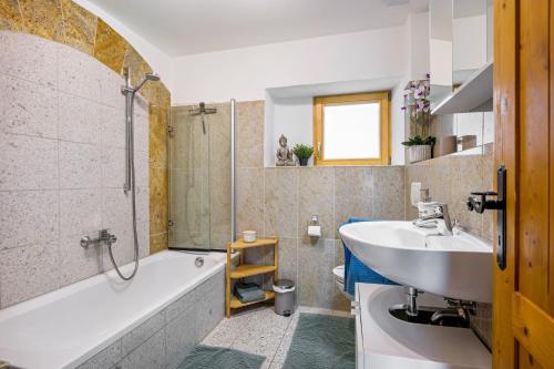 a bathroom with a tub and a sink and a shower at Ferienwohnung mit Bergblick in Edling