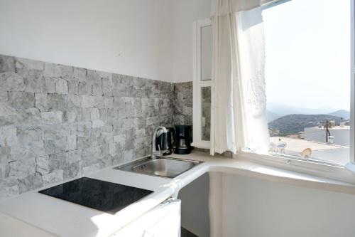 a white kitchen with a sink and a window at Politimis Studio N4 in Amorgos