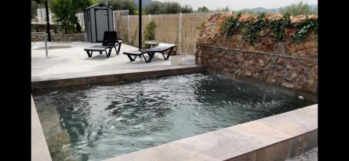 a pool of water next to a stone wall at Casa de Antonio con piscina privada in Moratalla