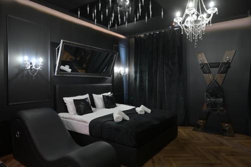 a bedroom with a bed and a chair and a chandelier at Love Krak-Off - BDSM Old Town in Krakow