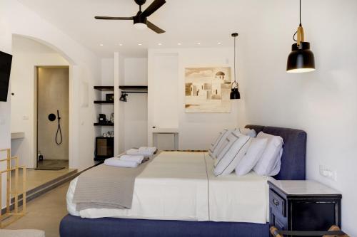 a bedroom with a large white bed and a ceiling fan at Blueros - Black Stone Suite in Megas Gialos - Nites