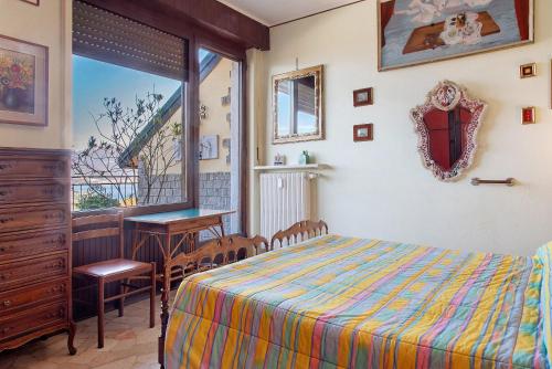 a bedroom with a bed and a table and a window at L'attico Con Terrazza Vista Lago in Laveno-Mombello