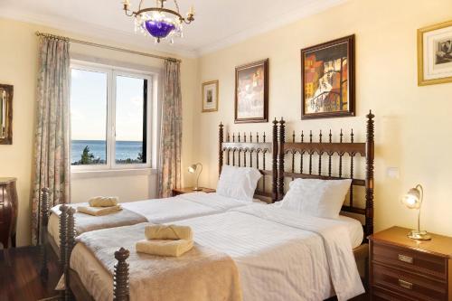 two beds in a bedroom with a view of the ocean at Bela Sao Tiago 36 in Funchal