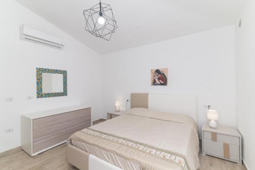 a white bedroom with a bed and a mirror at Casa Virgi vista mare in Budoni