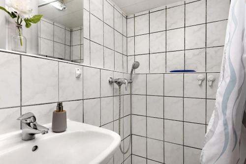 a white tiled bathroom with a sink and a shower at Sleep And Go in Mundelsheim