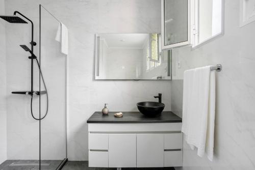 a white bathroom with a sink and a shower at Casa Caminho do Palheiro - Funchal in Funchal