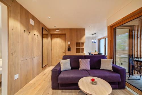 a living room with a purple couch and a table at Huetterhof Apartement Winter in Caines