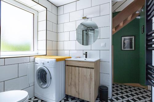 a bathroom with a washing machine and a sink at L'Arche aux Peyruches in Assieu