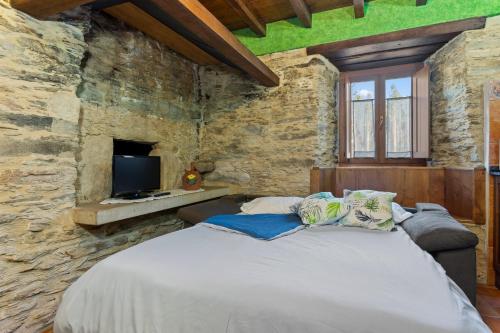a bedroom with a large bed in a stone wall at Eiron in O Porto de Espasante