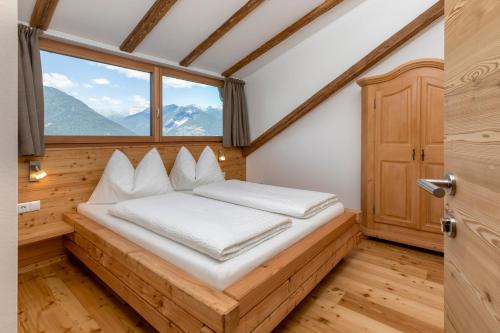 a bed in a room with a large window at Vernalhof Apt Panorama in Sluderno