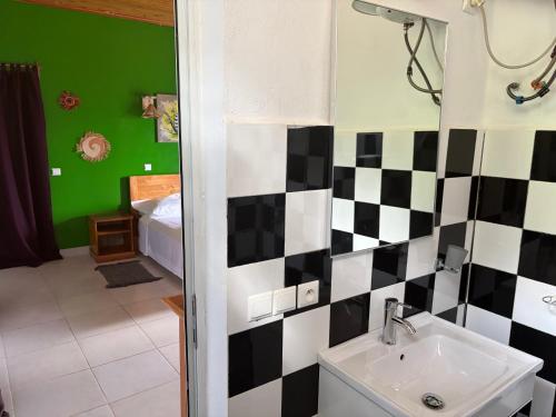 a bathroom with a black and white checkered wall at Villa Baby lodge in Hell-Ville