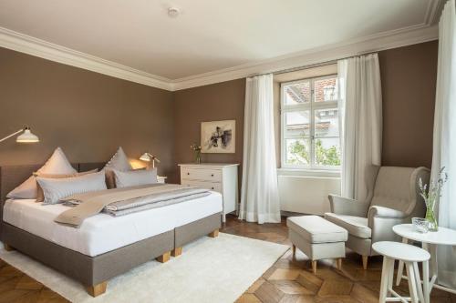 a bedroom with a bed and a chair and a window at Schloss Kirchberg - Rose in Immenstaad am Bodensee