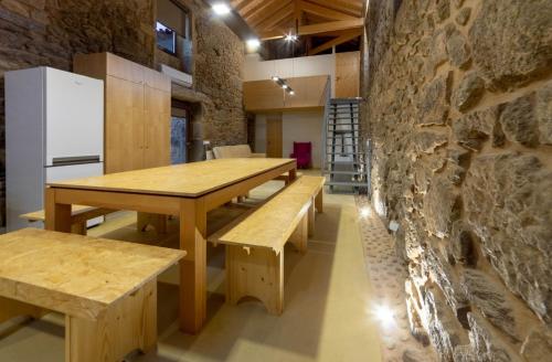 a room with wooden tables and benches and a stone wall at Villae Carreiro in Palmeira