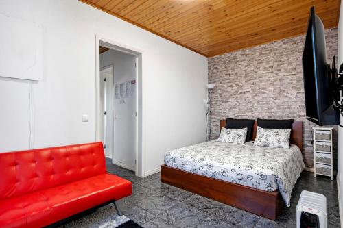 a bedroom with a bed and a red couch at Casinha do Monte in Achadinha