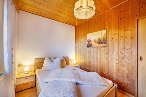 a bedroom with wooden walls and a bed with white sheets at Wohnung Elstar Schnalserhof in Laces