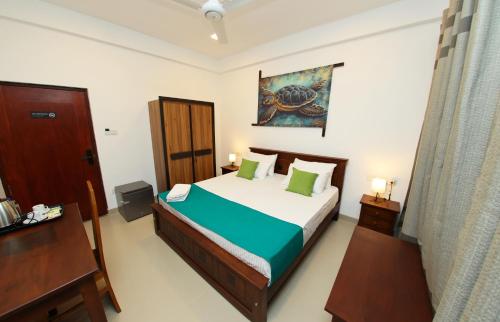 a bedroom with a bed with green pillows at Hotel Emerald Green in Weligama