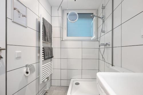 a white bathroom with a sink and a window at Apartment am Wald in Dörentrup