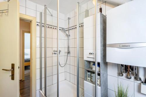 a shower in a bathroom with white tiles at Ferienwohnung Schlossbergblick in Arnsberg