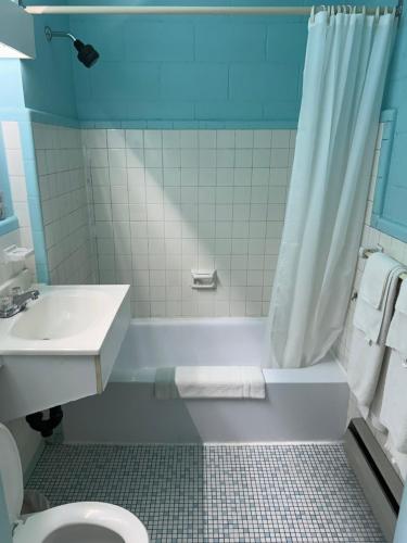 a bathroom with a tub and a sink and a toilet at Motel R-100 in Longueuil