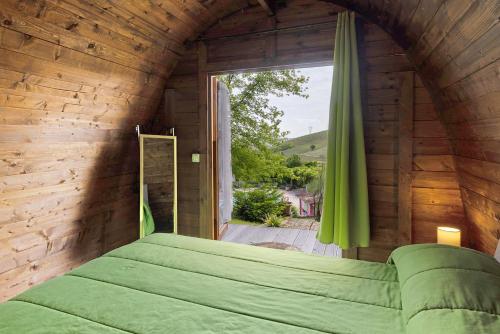 a bedroom with a green bed and a large window at Cascina Manzo in Dogliani