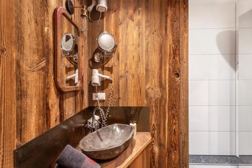 a bathroom with a sink and a wooden wall at Chalet Alpenherz in Inzell